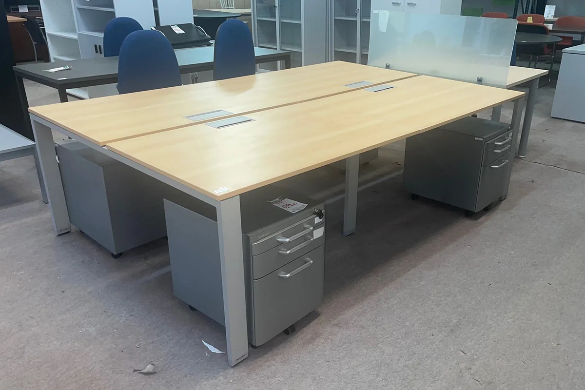 Mesas de oficina de cuatro puestos con cajoneras metálicas debajo del tablero