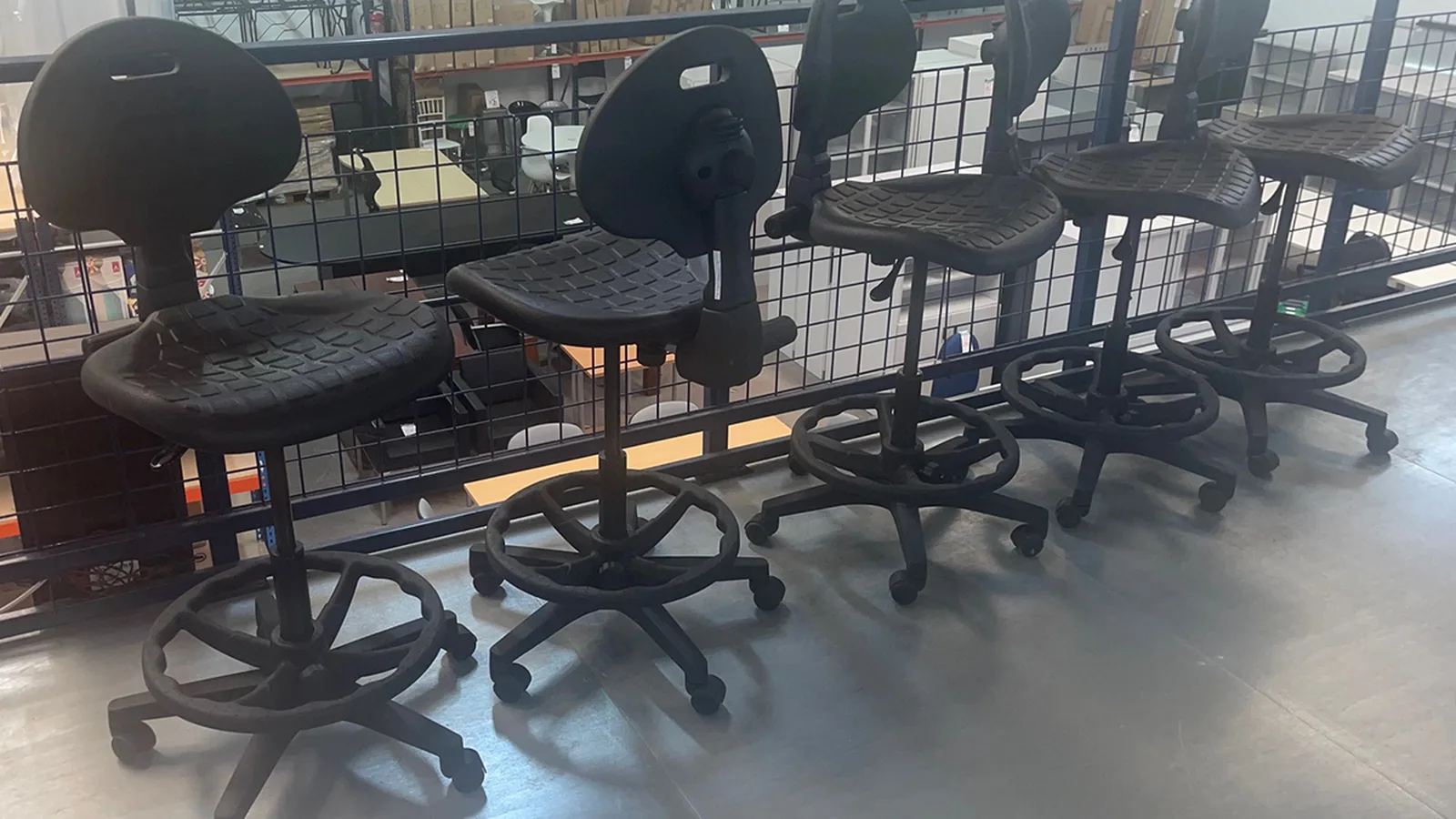 Altura de un taburete de trabajo: cinco taburetes de poliuretano con aro reposapiés y ruedas, a distintas alturas, en la nave de Muebles Talego